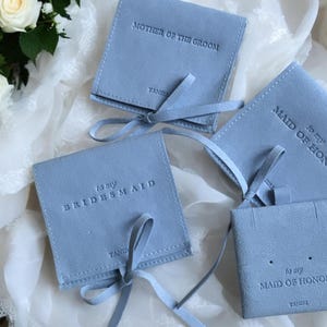May include: Four light blue velvet gift bags with satin ribbon ties. The bags are labelled with the text "to my bridesmaid", "to my maid of honour", and "mother of the groom".