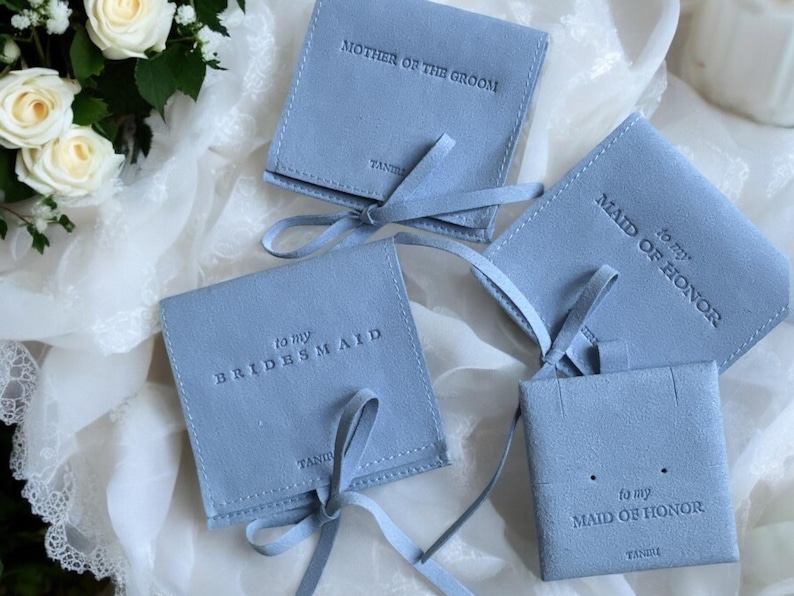 May include: Four light blue velvet gift bags with satin ribbon ties. The bags are labelled with the text "to my bridesmaid", "to my maid of honour", and "mother of the groom".