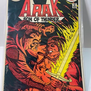 May include: A comic book cover featuring a red and yellow illustration of two men fighting. The comic book is titled "Arak, Son of Thunder" and is issue number 1 of the 198 annual. The cover is in good condition.