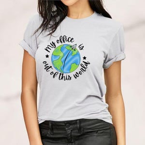 May include: A grey t-shirt with a graphic of a blue and green earth with a rocket ship flying over it. The text "My office is out of this world" is written around the earth.