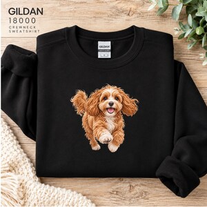 May include: A black crewneck sweatshirt featuring a graphic of a brown and white curly-haired dog running. The text GILDAN 18000 CREWNECK SWEATSHIRT is printed in the top left corner. The garment has a Gildan brand label at the inner neckline.