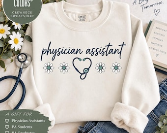 May include: A cream-colored crewneck sweatshirt featuring the text physician assistant in dark blue script, accompanied by a graphic of a stethoscope shaped like a heart and four small daisies with light green centers and white petals.