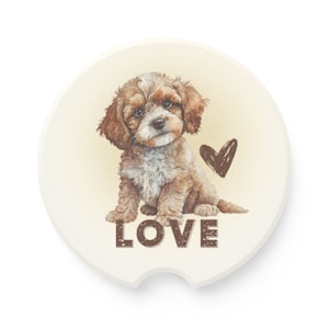 May include: A round, white ceramic coaster with a brown and white puppy sitting on a yellow background. The puppy is looking at the viewer. The text "LOVE" is printed in brown letters below the puppy. A brown heart is drawn to the right of the puppy.