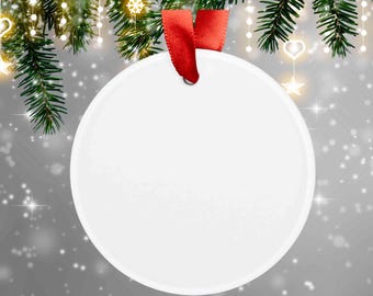 Puede incluir: Un adorno circular de cerámica blanca con una superficie lisa y en blanco. El adorno presenta un pequeño orificio en la parte superior, a través del cual se pasa y se ata una cinta de satén rojo brillante para colgarlo como decoración.