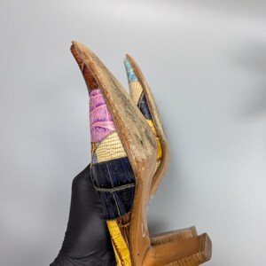 May include: A pair of high-heeled shoes with a patchwork design. The shoes feature a variety of colors, including brown, yellow, purple, and blue. The heels are made of wood.