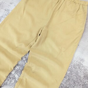 May include: A pair of solid light tan trousers featuring a comfortable elasticized waistband. The pants are crafted from a smooth, plain-weave fabric and showcase a simple, straight-leg cut with clean lines and no visible pockets or decorative details.
