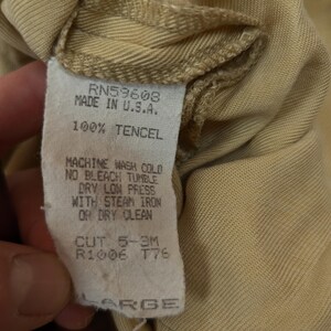 May include: A tan-colored garment tag featuring the text RN59608, MADE IN U.S.A., 100% TENCEL, MACHINE WASH COLD, NO BLEACH, TUMBLE DRY LOW, PRESS WITH STEAM IRON OR DRY CLEAN, CUT 5-3M, R1006, T76, and the size label LARGE in capital letters.