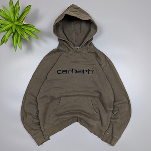 Puede incluir: Sudadera con capucha Carhartt verde oliva con capucha y bolsillo delantero. El nombre de la marca est&aacute; bordado en negro en el pecho. La sudadera est&aacute; hecha de un material suave y c&oacute;modo.