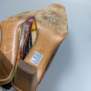May include: Pair of brown leather heeled shoes with a square toe. The soles are worn, and the heels are a medium height. The shoes are marked "Made in Italy" and size 37 1/2.