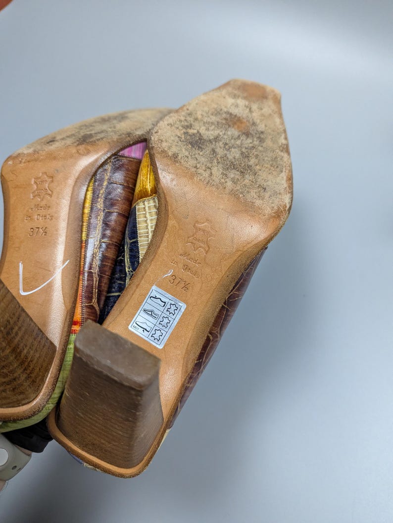 May include: Pair of brown leather heeled shoes with a square toe. The soles are worn, and the heels are a medium height. The shoes are marked "Made in Italy" and size 37 1/2.