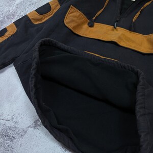 Pode incluir: Um moletom preto com capuz apresentando um grande painel horizontal de cor castanha no peito e remendos a condizer nas mangas. A pe&ccedil;a inclui um decote com meio fecho de correr, capuz com cord&atilde;o e um interior forrado com tecido polar preto.