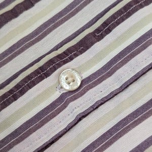 K&ouml;nnte beinhalten: Nahaufnahme eines gekn&ouml;pften Hemdes mit Streifenmuster. Das Hemd hat abwechselnd wei&szlig;e, hellgr&uuml;ne und dunkelviolette Streifen. Ein wei&szlig;er Knopf ist auf der Knopfleiste zu sehen. Der Stoff scheint Baumwolle oder ein &auml;hnliches Material zu sein.