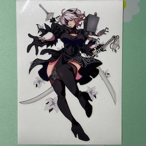 May include: A sticker featuring a stylized anime character in a black dress, thigh-high stockings, and high heels, holding two swords. The character has white hair and is surrounded by white flower accents. The background is a light green.