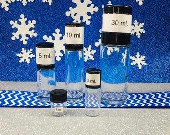 May include: A collection of clear glass bottles with black caps and white labels, each marked with a milliliter measurement: 1 ml, 3 ml, 5 ml, 10 ml, and 30 ml. The bottles are arranged on a silver and blue background with snowflake decorations.