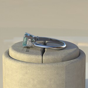 May include: A silver ring with a large emerald-cut aquamarine gemstone and smaller baguette-cut diamonds on the band.