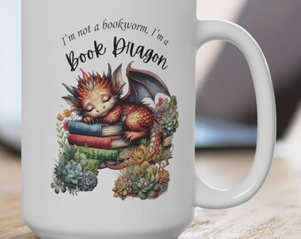 Op de afbeelding: Een witte keramische mok met een rode en oranje draak die slaapt op een stapel boeken. De mok heeft de tekst "I'm not a bookworm, I'm a Book Dragon" erop gedrukt.