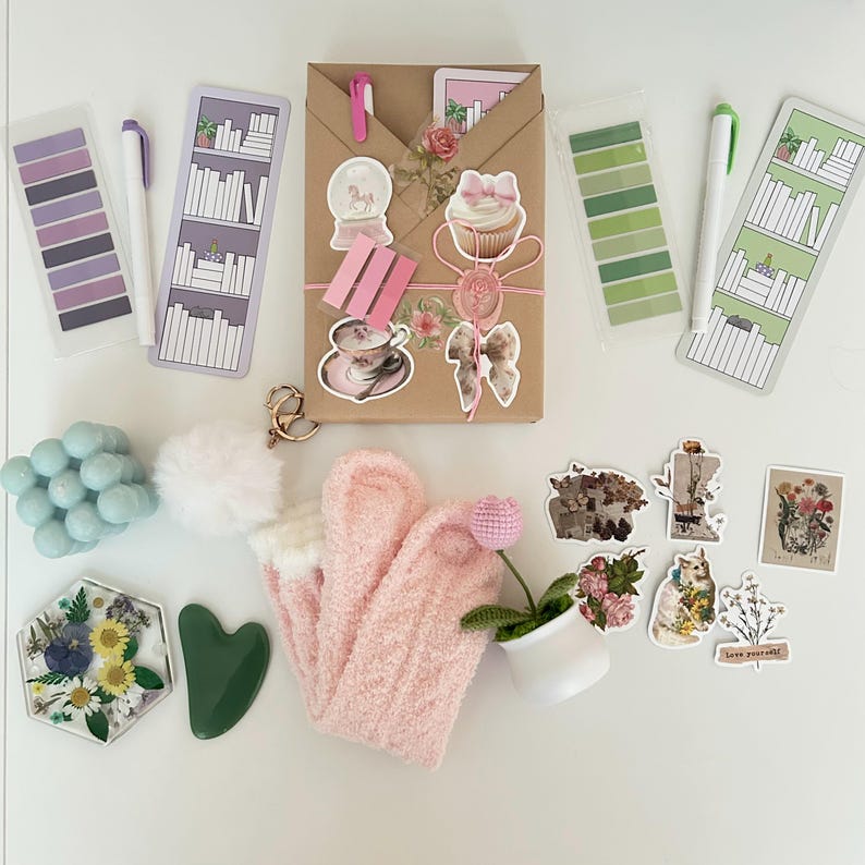 May include: A collection of craft supplies including a brown paper package with stickers, a pink fuzzy sock, a green heart-shaped tool, a small potted plant, a white pom-pom, a blue bubble bath, and a variety of stickers with floral and animal designs.