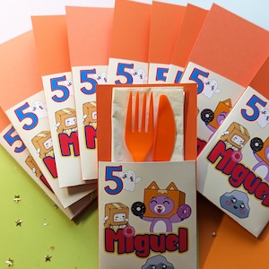 May include: Orange and cream colored party favor boxes with a cartoon character on the front. The boxes are decorated with the number 5 and the name Miguel. The boxes are filled with a fork, knife, and napkin.