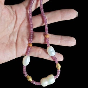 Puede incluir: Un collar de piedras preciosas rosas con detalles dorados y perlas blancas.