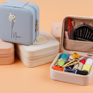 K&ouml;nnte beinhalten: Vier verschiedene quadratische Etuis mit Rei&szlig;verschluss. Ein Etui ist hellblau mit einem Blumenmuster und dem Text "Name". Ein weiteres Etui ist cremefarben mit einem Blumenmuster und dem Text "Good Vibes". Ein drittes Etui ist hellrosa mit dem Text "Inspire". Das vierte Etui ist cremefarben mit einem Rei&szlig;verschlussfach, das eine Vielzahl von N&auml;hzubeh&ouml;r enth&auml;lt, darunter Nadeln, Garn und eine Schere.