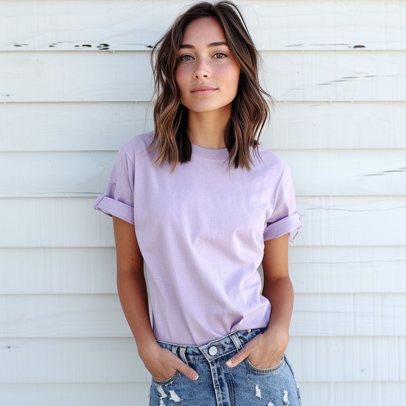 May include: A woman wearing a light purple t-shirt with rolled up sleeves and blue denim jeans.