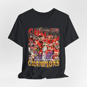 May include: Black t-shirt with a graphic of the Kansas City Chiefs football team celebrating their Super Bowl victory. The graphic features the team's logo, the number "VII", and the text "Back to Back Super Bowl Champions".