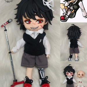 Puede incluir: Una muñeca hecha a mano con cabello negro, una camisa blanca, un chaleco negro, pantalones cortos grises y zapatos rojos. La muñeca tiene un soporte de micrófono y una pierna de esqueleto. La muñeca lleva un lazo blanco. La muñeca también se muestra en diferentes poses, incluyendo un primer plano de la cara y una toma de cuerpo completo.