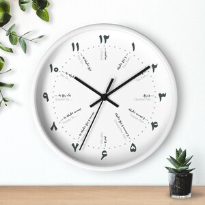 Puede incluir: Un reloj de pared redondo blanco con manecillas negras y números arábigos. La esfera del reloj tiene marcas para cinco, diez, quince, veinte, veinticinco y treinta minutos después de la hora, así como cinco, diez, quince, veinte y veinticinco minutos antes de la hora. La esfera del reloj también tiene marcas para cuarto de hora, media hora y cuarto de hora antes de la hora. La esfera del reloj está en farsi.