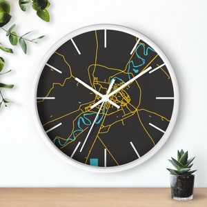 May include: A white clock with black face and yellow and blue map design. The clock face features a map of a city with a river running through it.