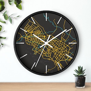 May include: Black and white clock with a map of a city printed on the face. The map is in yellow and blue. The clock has white hands.