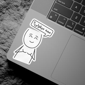 Könnte beinhalten: Ein weißer Aufkleber auf einem Laptop mit einem Comic-Gesicht und einer Sprechblase, auf der in Arabisch "ممه میقولی?" steht.