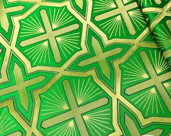 May include: Green and gold fabric with a geometric pattern of crosses and sunbursts. The fabric has a subtle sheen and a textured surface. The number "3" is visible in the lower right corner of the image.