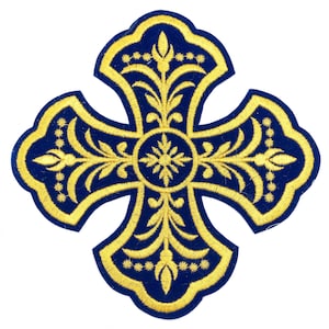 May include: A gold embroidered cross with intricate floral designs on a dark blue velvet background.