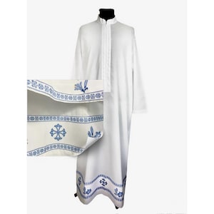 May include: White liturgical robe with blue embroidered trim featuring a cross and floral designs. The trim is visible on the bottom of the robe and the sleeves.