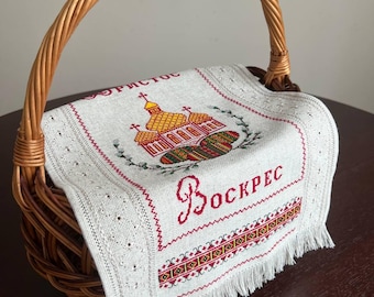 May include: A white linen Easter basket liner with red embroidered lettering that says "Bockpec" and a church with a yellow dome and red crosses. The liner has a fringe border and is in a wicker basket.
