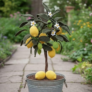 May include: A handcrafted crochet lemon tree in a galvanized metal pot. The tree features yellow lemons, green unripe lemons, white flowers, and dark green leaves. Two yellow lemons rest at the base of the tree. The tree is a unique home decor item.