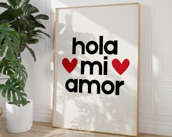 May include: A white framed print with the text "hola mi amor" in black with two red hearts.