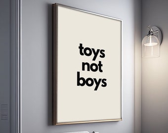 May include: A framed print with the text "toys not boys" in black lettering on a cream background.