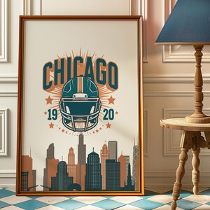 May include: Framed art print with a teal and orange football helmet and the word "CHICAGO". The print includes the year "19 20" and a city skyline silhouette. The artwork is presented in a brown frame.