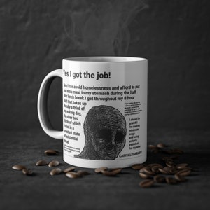 Könnte beinhalten: Eine weiße Keramiktasse mit einer Schwarzweißillustration eines menschlichen Gesichts und dem Text "Yes I got the job! Now I can avoid homelessness and afford to put one extra meal in my stomach during the half hour lunch break I get throughout my 8 hour shift that takes up literally a third of my waking day, the other two thirds of which exist in a constant state of existential dread. I should be grateful I'm making minimum wage and being unfairly exploited for my labor. CAPITALISM BABY!"