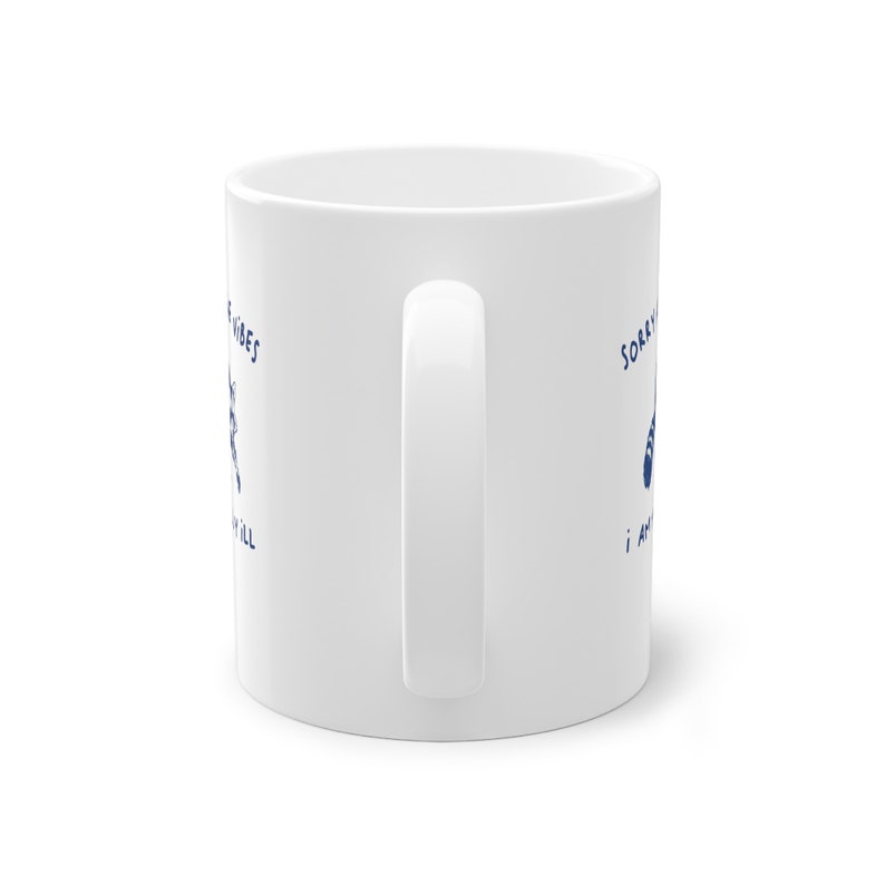 White ceramic mug with funny raccoon meme and caption Sorry About the Vibes, I Am Mentally Ill