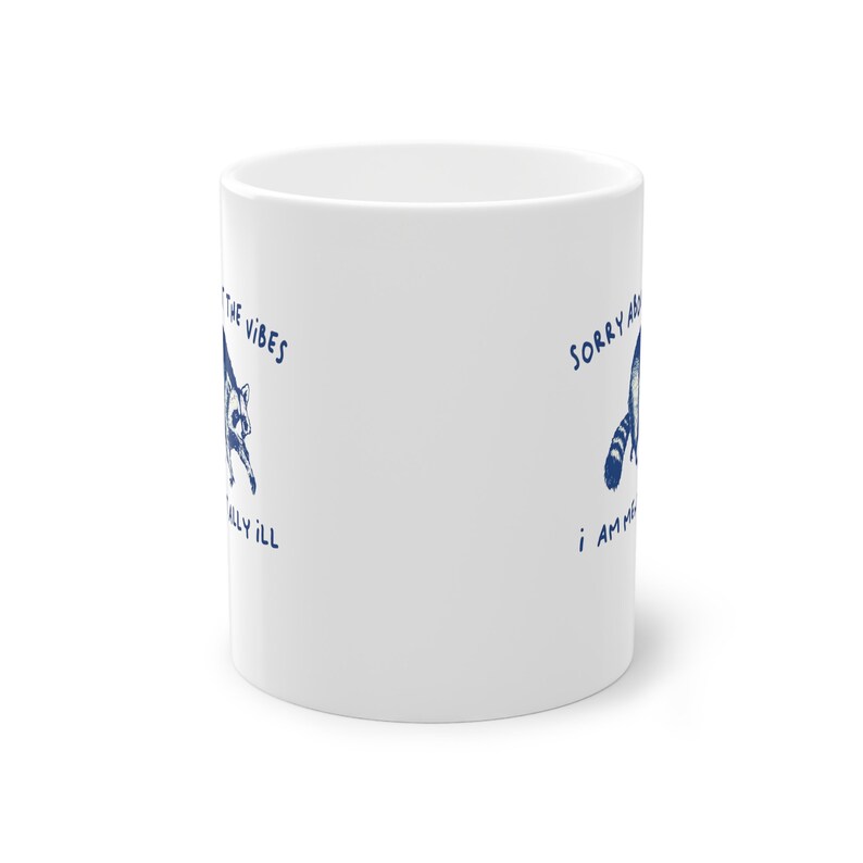 White ceramic mug with funny raccoon meme and caption Sorry About the Vibes, I Am Mentally Ill