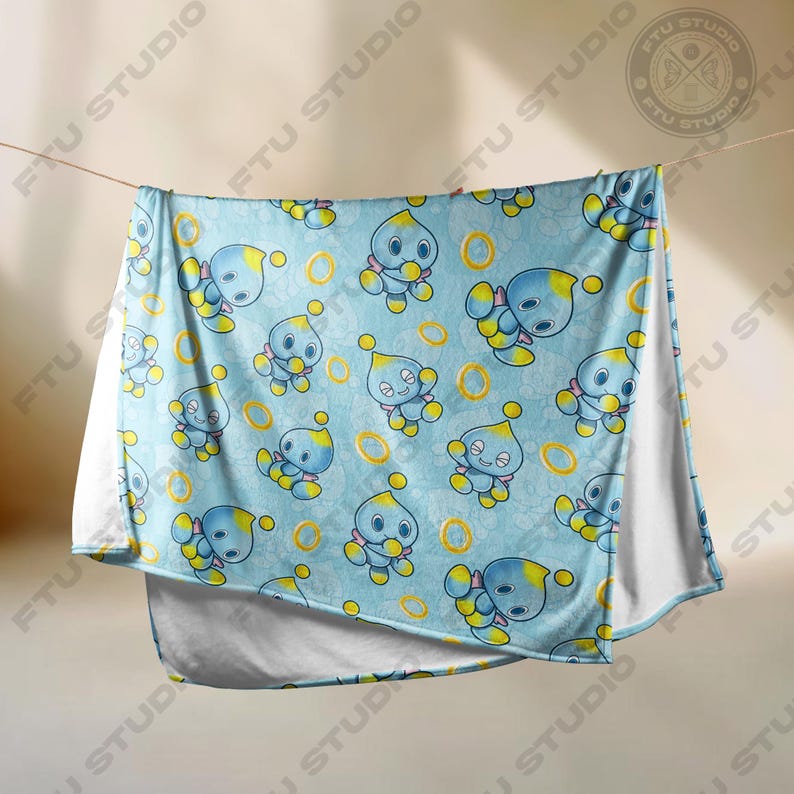 May include: A blue and yellow fleece blanket with a repeating pattern of a blue character with yellow accents and a gold ring. The character is on a light blue background.