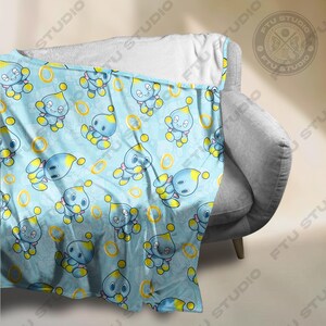 May include: A blue and yellow fleece blanket with a repeating pattern of a blue character with yellow accents and gold rings.