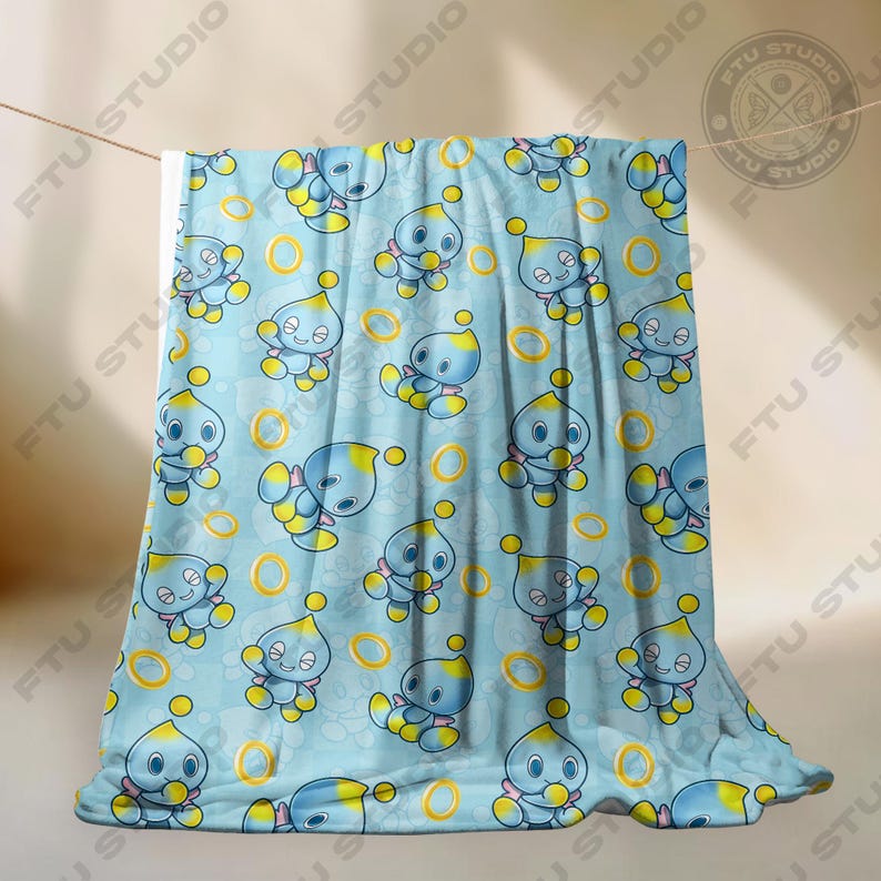 May include: A blue and yellow fleece blanket with a repeating pattern of a blue cartoon character with yellow eyes and a yellow ring.