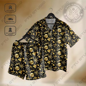 Könnte beinhalten: Schwarzes Hemd und Shorts mit einem sich wiederholenden goldenen Muster aus Ankhs, Augen und anderen Symbolen. Das Set hängt an einem schwarzen Kleiderbügel. Die Shorts haben einen Kordelzug.