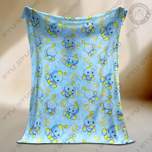 May include: A blue fleece blanket with a repeating pattern of a blue and yellow cartoon character with a ring around it.