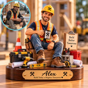 Könnte beinhalten: Eine Figur eines Bauarbeiters mit gelbem Schutzhelm und orangefarbener Warnweste, die auf Holzbalken sitzt. Der Sockel ist mit einer Messingplakette versehen, die den Namen Alex und den Text Build Today a Brighter Tomorrow trägt.