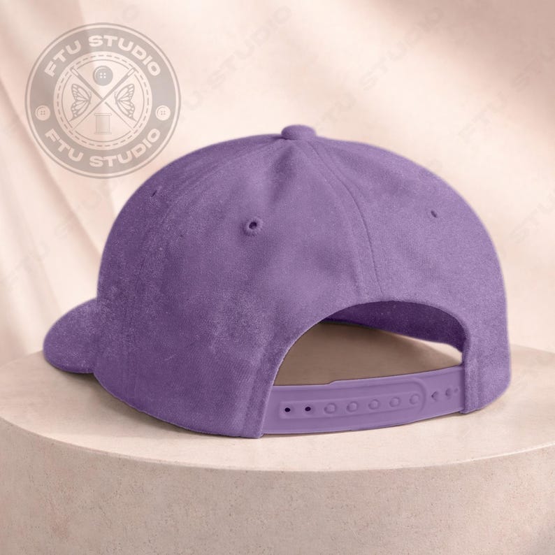 May include: A solid lavender baseball cap with a curved brim and adjustable snapback closure. The cap features a rounded crown and a small button on top. The back of the cap has a plastic strap for size adjustment.