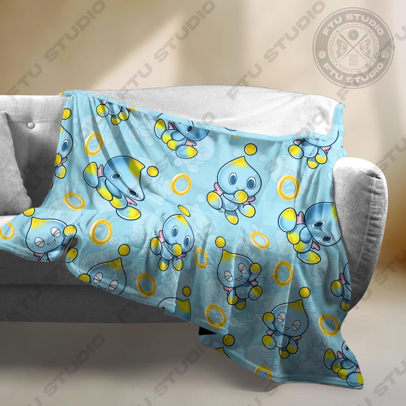 May include: A blue fleece throw blanket with a repeating pattern of a blue and yellow cartoon character with a yellow ring.